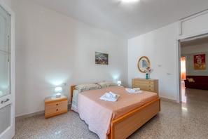 Une chambre à coucher avec un lit, des tables de chevet, un miroir et un tableau accroché au mur.