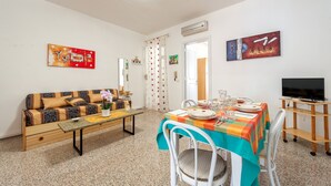 Une pièce comprenant un canapé, une table à manger, des chaises, un téléviseur et des œuvres d’art accrochées aux murs.