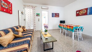Un salon avec un canapé, une table à manger et des chaises, ainsi que des œuvres d’art accrochées aux murs.