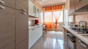 Une cuisine compacte comprenant un coin repas, une cuisinière à gaz et une fenêtre avec des rideaux.