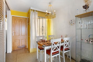 A dining area with a table set for four, a chandelier, and a glass cabinet with decorative items.
