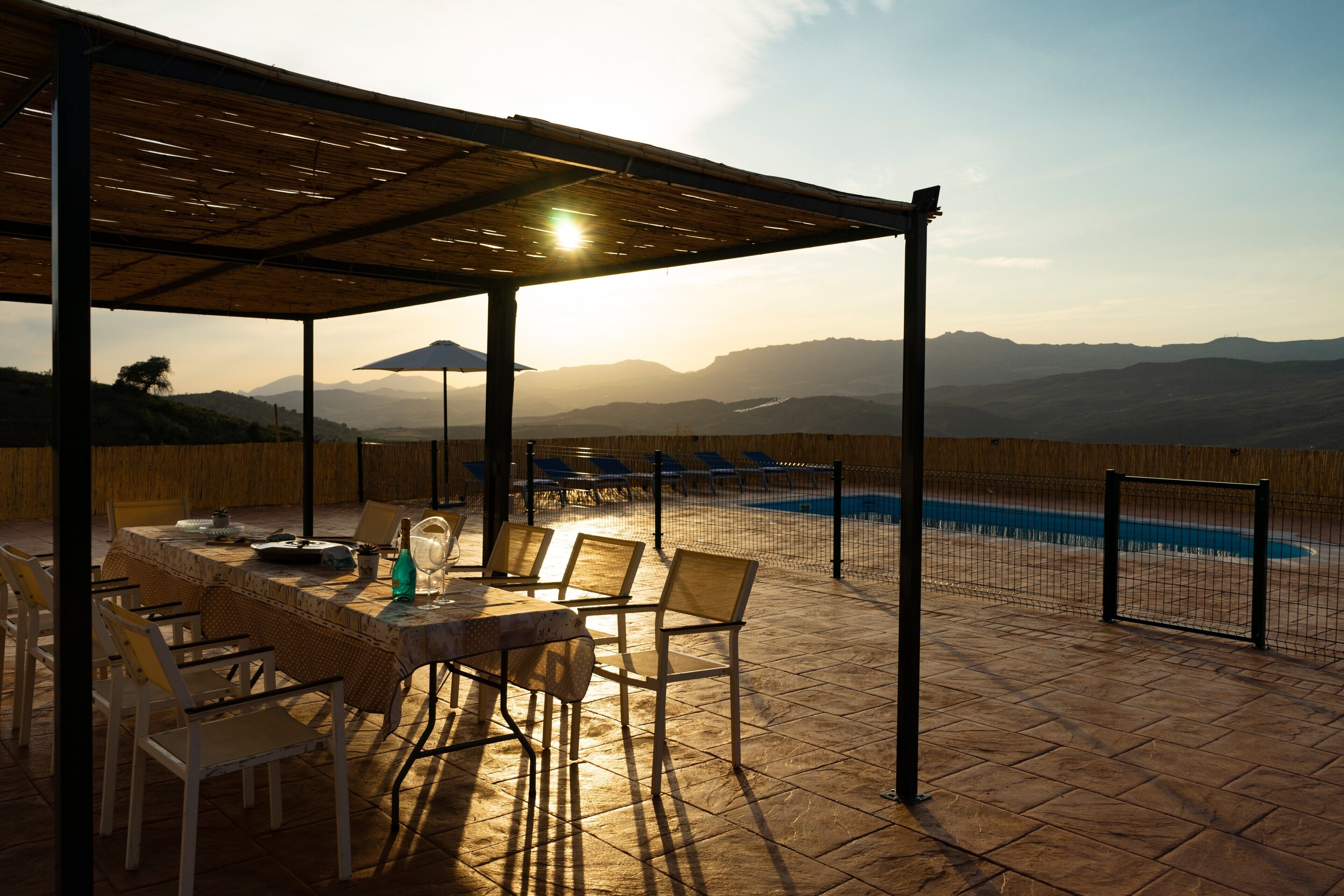An outdoor dining area with a pool, chairs, and a table.