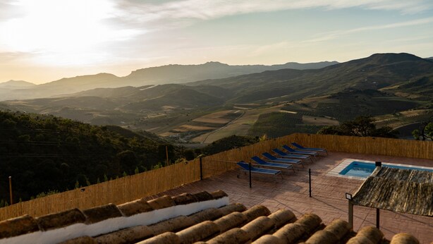 Terraza en la azotea con piscina, sillas de descanso y vistas a colinas ondulantes.