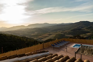 Terraza en la azotea con piscina, sillas de descanso y vistas a colinas ondulantes.