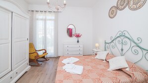 A bedroom with a bed, a rocking chair, a dresser, a mirror, and wall art.
