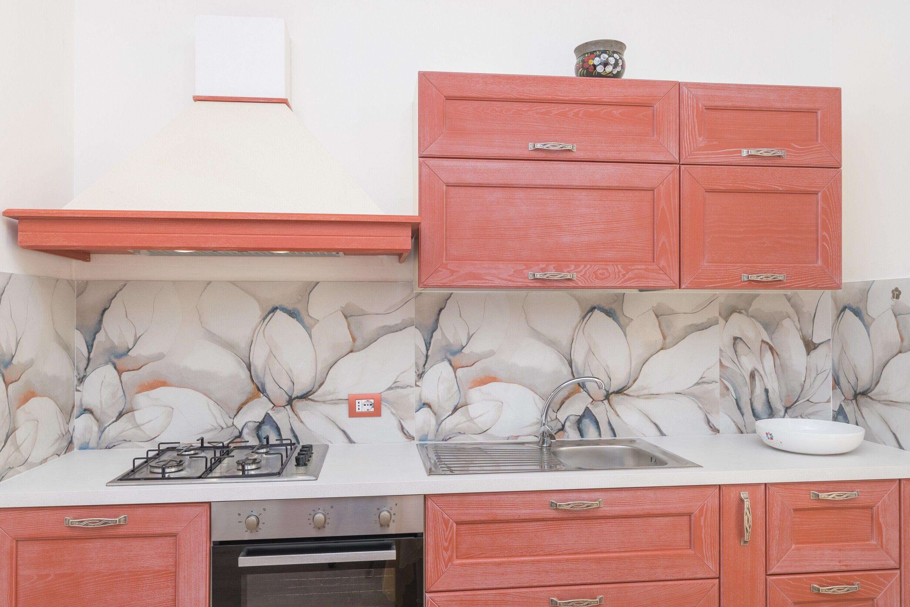 Una cocina con estufa a gas, horno, lavaplatos y armarios rojos.