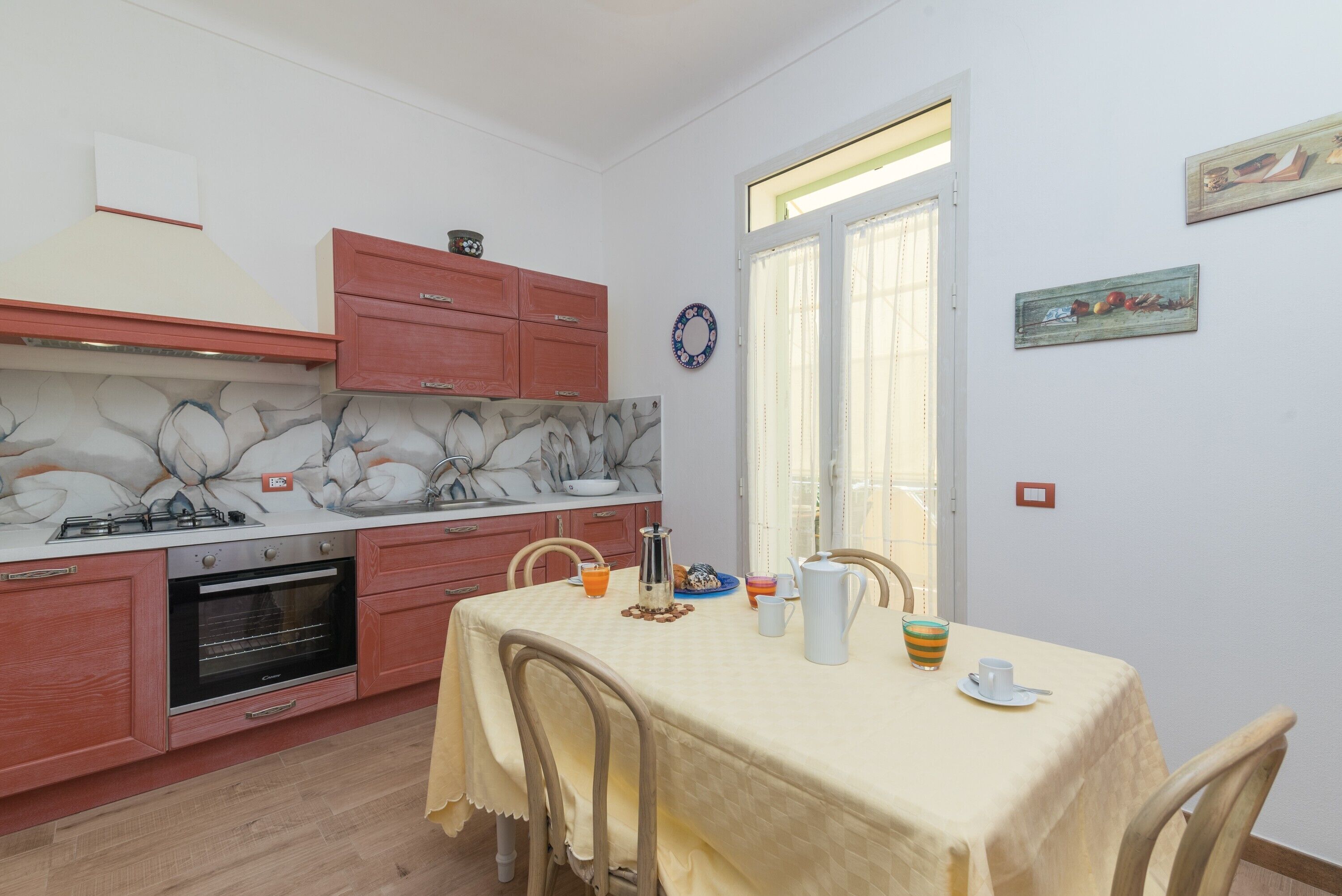 Una cucina con tavolo e sedie, piano cottura, forno e una finestra con tende.