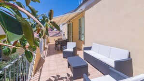 A balcony with wicker furniture, a table, and chairs.