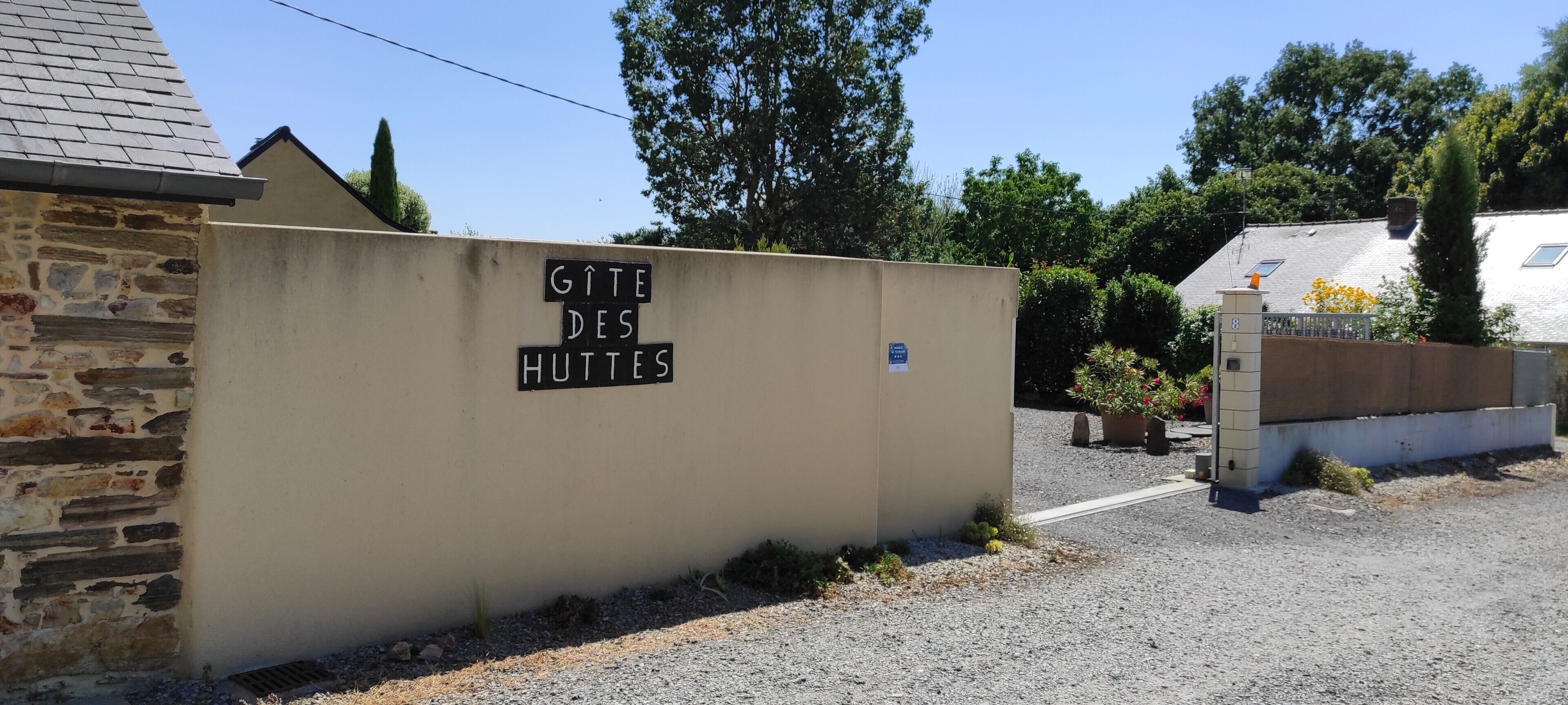 Eine beige Wand mit einem Schild, auf dem 'GITE DES HUTTES' steht.