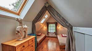 A bedroom with a sloped ceiling, a wooden dresser, two beds, a window, and a decorative horse statue.