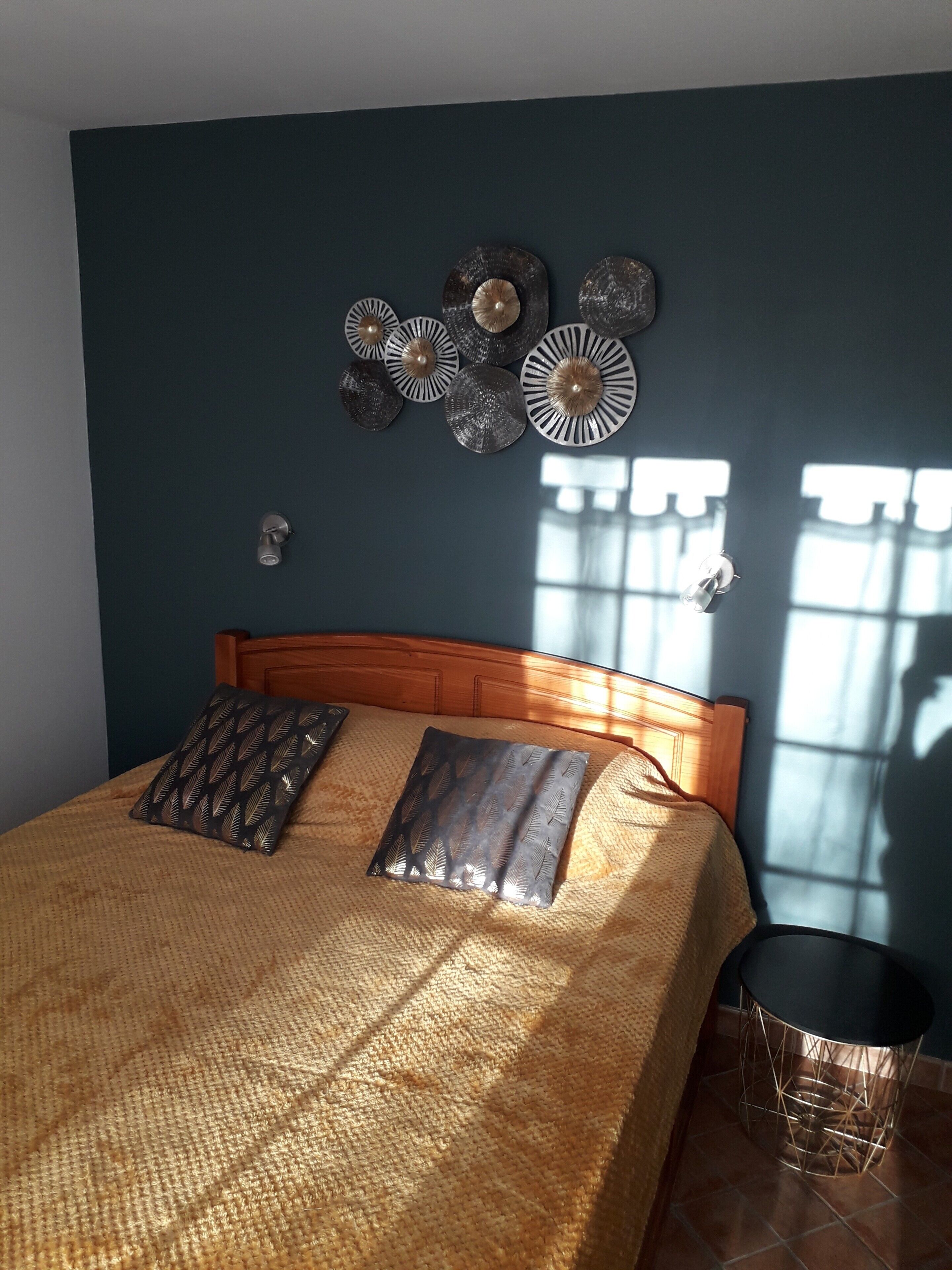 Ein Bett mit einem Holz-Kopfteil, einer gewebten Decke und dekorativen Kissen.