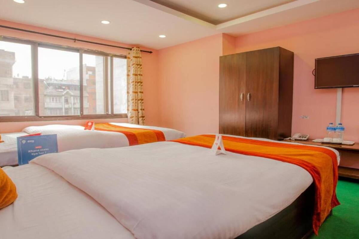 A hotel room with two beds, a wardrobe, a television, and a window with curtains.