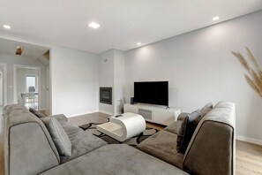 A modern living room with a grey sofa, a white coffee table, and a flat-screen TV on a white entertainment unit. - Holiday Home 'Sunset' with Private Pool, Wi-Fi and Air Conditioning (Fernão Ferro)