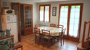 Un coin repas comprenant une table ronde, six chaises, un réfrigérateur et un four à micro-ondes.