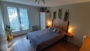 Un dormitorio con cama, lámparas de noche, armario y ventana con cortinas.