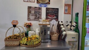 A coffee station with a coffee machine, baskets of fruits, and coffee mugs. - Sun Chakra Boutique Hotel (Phnom Penh)