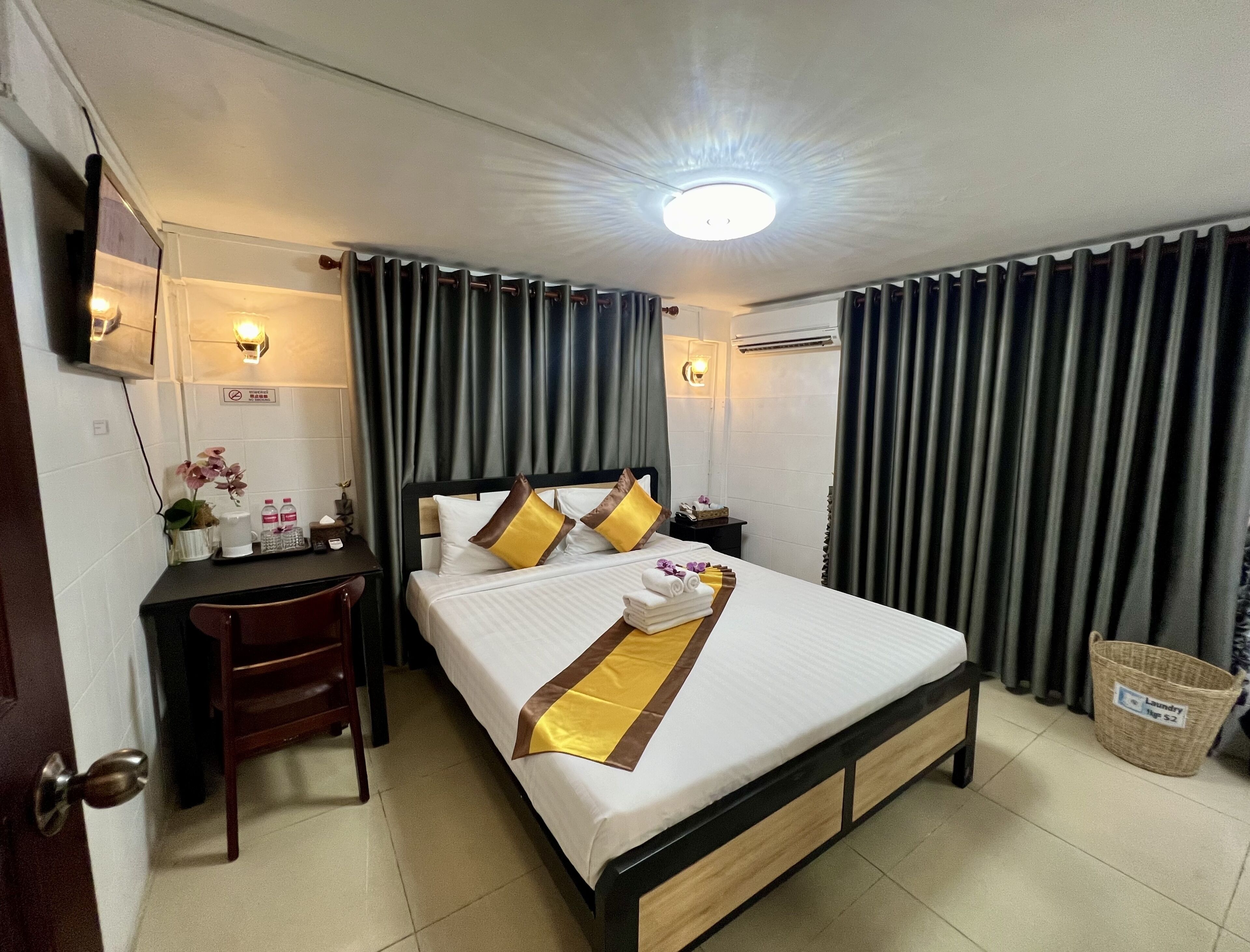 A hotel room with a bed, bedside table, lamp, and a mirror.