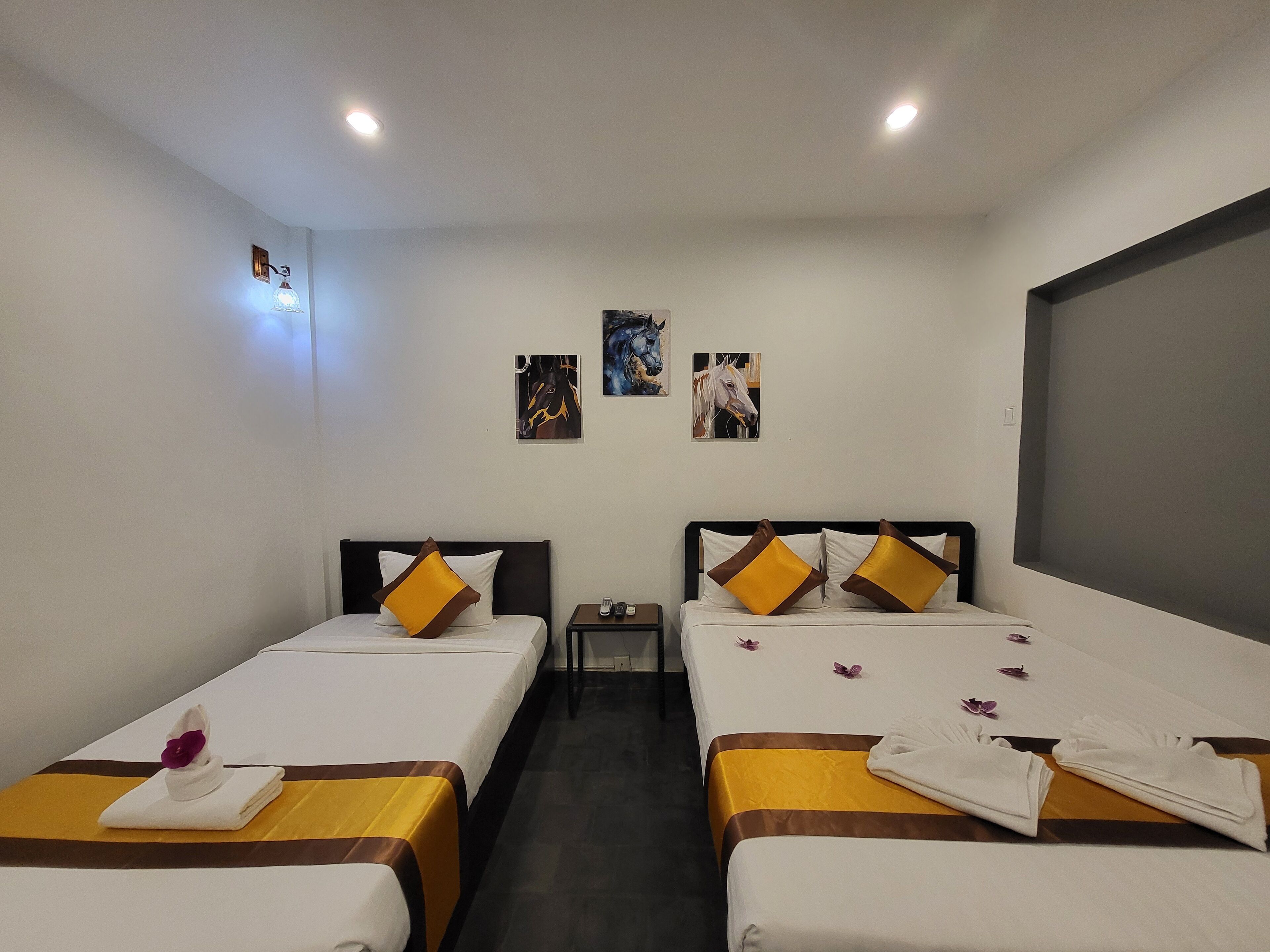 Ein Hotelzimmer mit zwei Betten, jedes mit einem Kissen und einem kleinen Tisch mit Telefon.