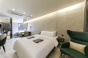 A modern hotel room with a large bed, a desk, a chair, and a green armchair. - Heritage31 Hotel (Seoul)