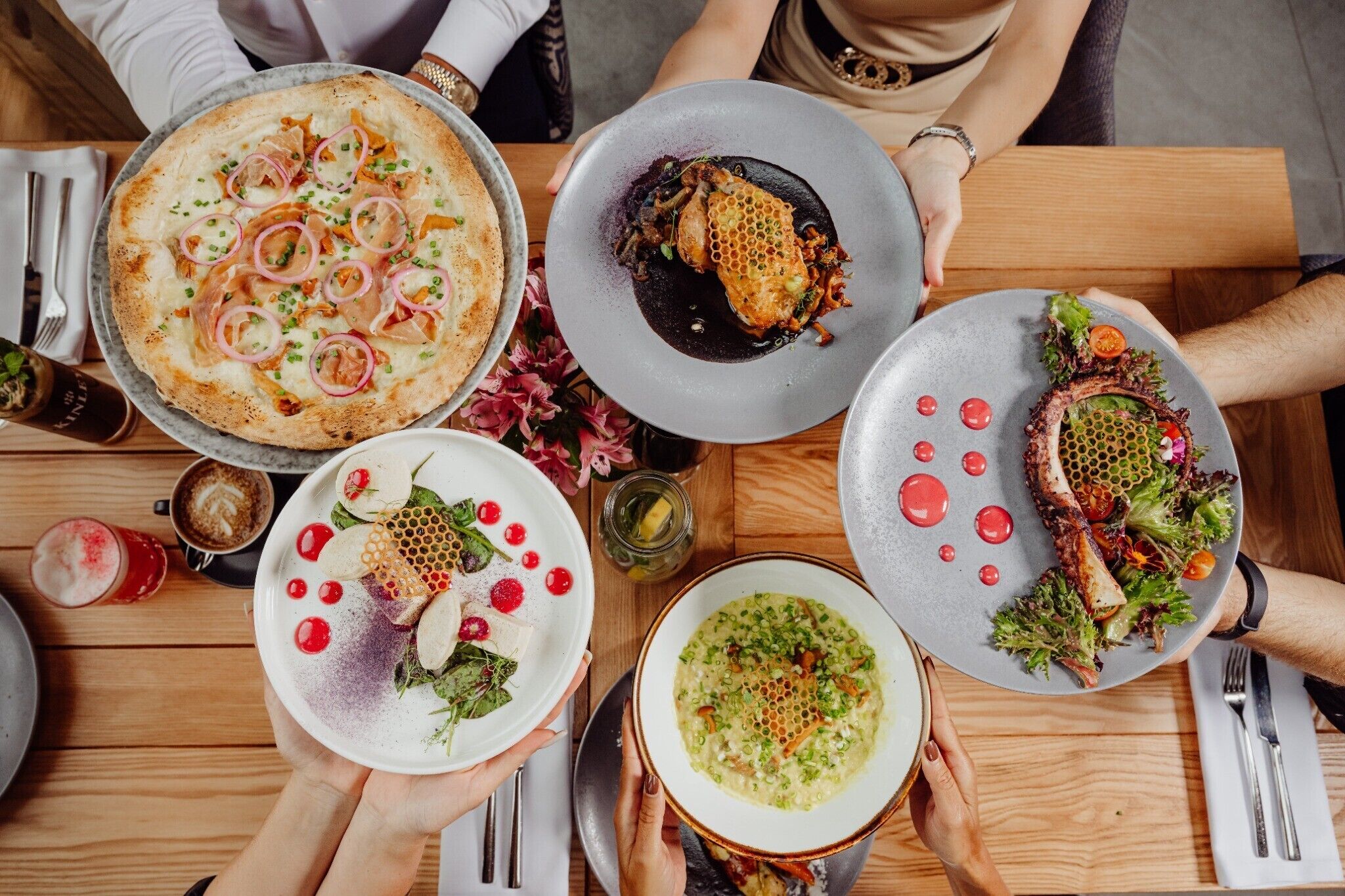 Una mesa de comedor con varios platos, entre ellos pizza, mariscos, ensalada y sopa.