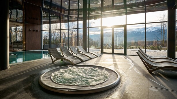 A spa area with a hot tub, lounge chairs, and a view of mountains through large windows. - Złoty Horyzont Resort Szklarska Poręba (Szklarska Poreba)
