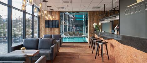 A modern bar area with seating, a pool view, and a large window.