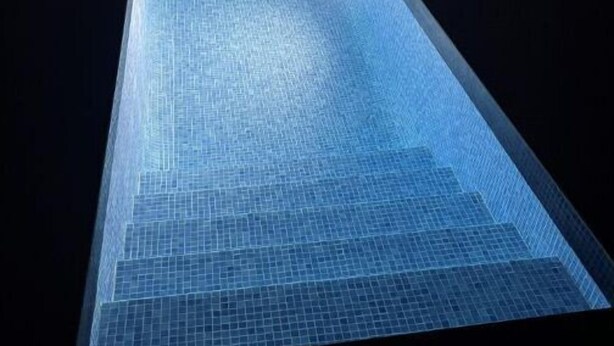 Piscina com chão em mosaico e área ao redor escura.