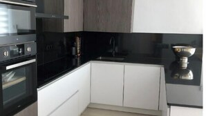Uma cozinha moderna com armários de madeira escura, bancada preta e forno de aço inoxidável.