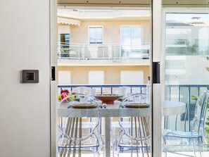 Ein Balkon mit Esstisch, transparenten Stühlen und Blick auf die Außenansicht des Gebäudes.