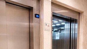 Een lift met een digitaal scherm, een brandveiligheidssignaal en een metalen binnenkant.