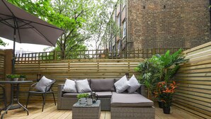 An outdoor patio with wicker furniture, a table, and potted plants. - Archway luxury interior designed 1 bed (London)
