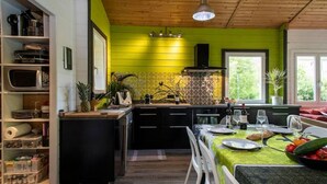 Een keuken met een groene wand, houten plafond en een eethoek met een tafel gedekt voor twee personen.