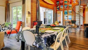 Een houten interieur met een eethoek, een wenteltrap en uitzicht op het omliggende landschap.