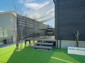 An outdoor patio area with a table and chairs, a covered seating area, and a hose for outdoor use.