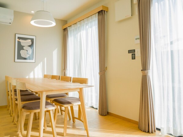 A dining area with a wooden table and chairs, a pendant light, and a framed picture on the wall.