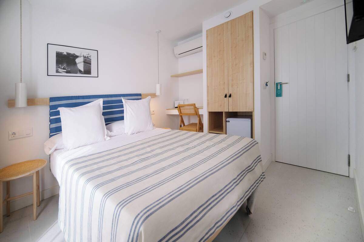 A bedroom with a bed, a chair, a wardrobe, and a picture on the wall.