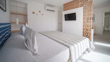 A bedroom with a bed, a TV, a wooden partition, and a white air conditioning unit.
