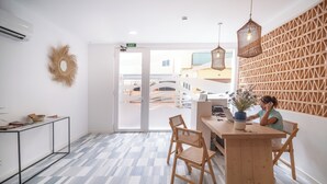 Un intérieur moderne avec un bureau en bois, deux chaises en osier, un luminaire suspendu et un sol à motifs.