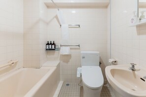 A bathroom with a bathtub, toilet, and sink, all in a neutral color scheme.