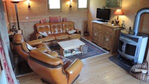 A cozy living room with a leather sofa, a television, a fireplace, and wooden walls. - Savoyard Chalet 8 pers, near slopes, parking (Crest-Voland)