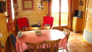 A cozy wooden cabin with a dining area featuring a checkered tablecloth, red chairs, and a television in the corner. - Savoyard Chalet 8 pers, near slopes, parking (Crest-Voland)
