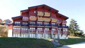 Ein mehrstöckiges Hotel mit Balkonen, einer Steinaußenwand und einem Parkplatz davor.