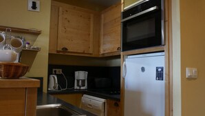 Eine kleine Küche mit Holdekor, einer Mikrowelle, einem Kühlschrank, einer Kaffeemaschine und einem Waschbecken.