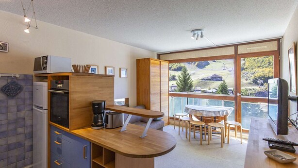 A modern kitchen with a built-in oven, a coffee maker, and a dining area with a table and chairs. - Studio cabin for 6 near ski slopes in Gourette, living room with balcony, parking (Gourette)