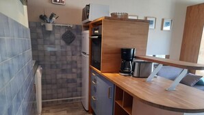 A compact kitchen with a refrigerator, coffee maker, and a microwave. - Studio cabin for 6 near ski slopes in Gourette, living room with balcony, parking (Gourette)