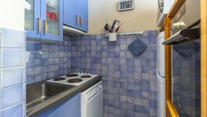 A compact kitchen with blue cabinets, a stove, a dishwasher, and a clock on the wall. - Studio cabin for 6 near ski slopes in Gourette, living room with balcony, parking (Gourette)