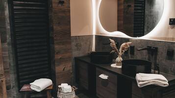 Une salle de bain moderne avec un mur en bois, un grand miroir et deux lavabos noirs.