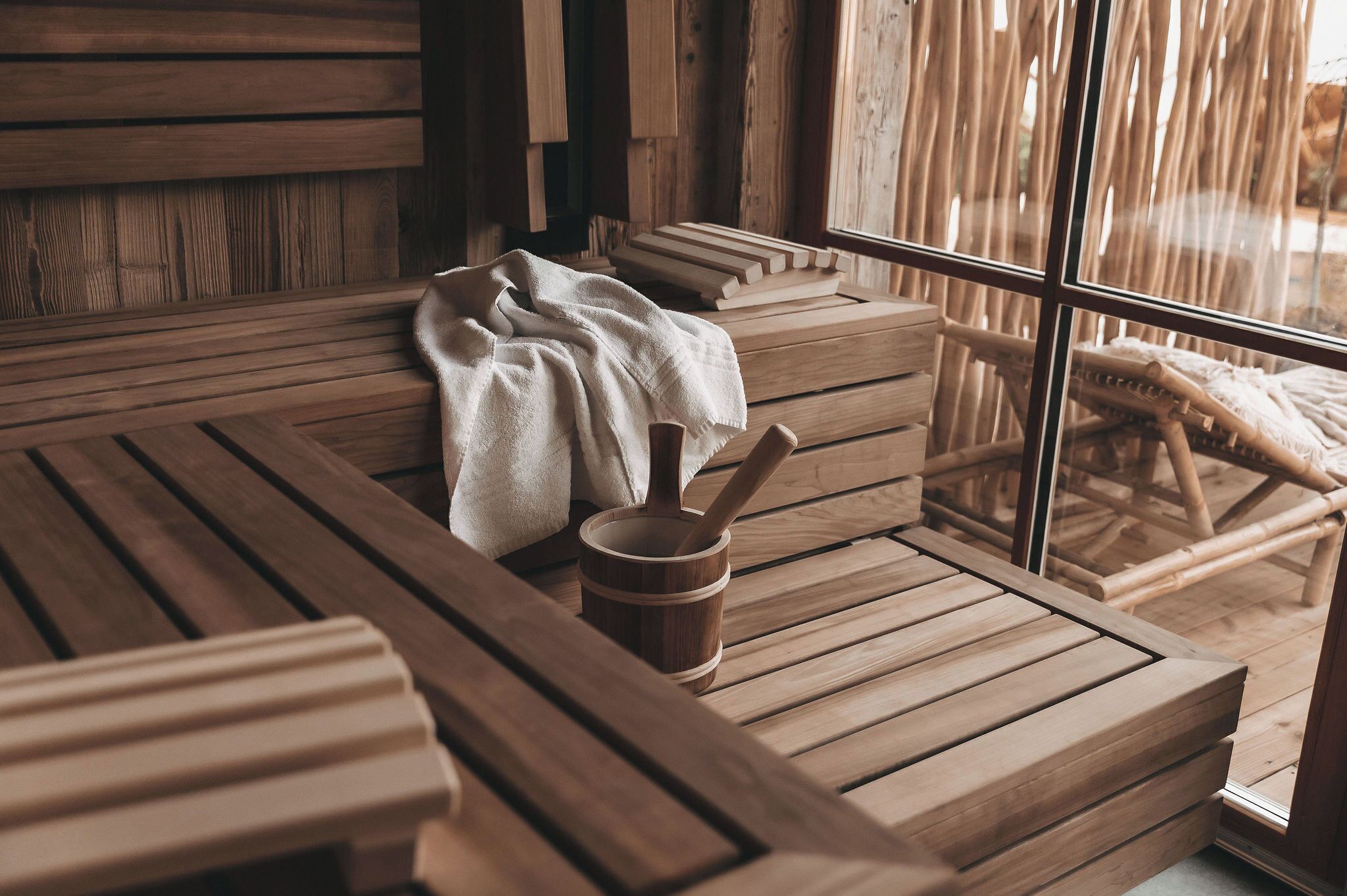 Un sauna en bois avec des bancs, une serviette et un seau en bois.