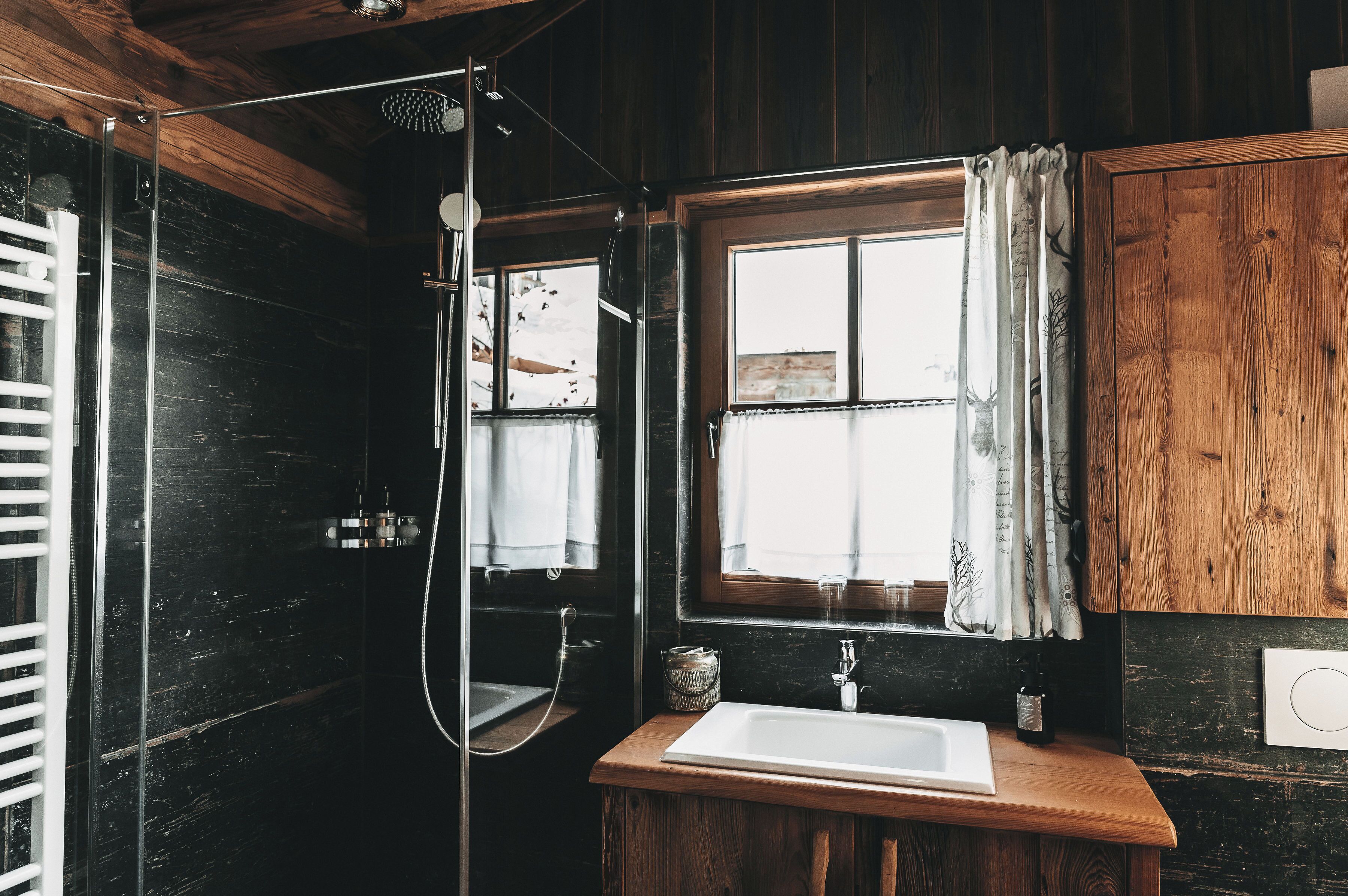 Un baño con tocador de madera, lavamanos y zona de ducha.