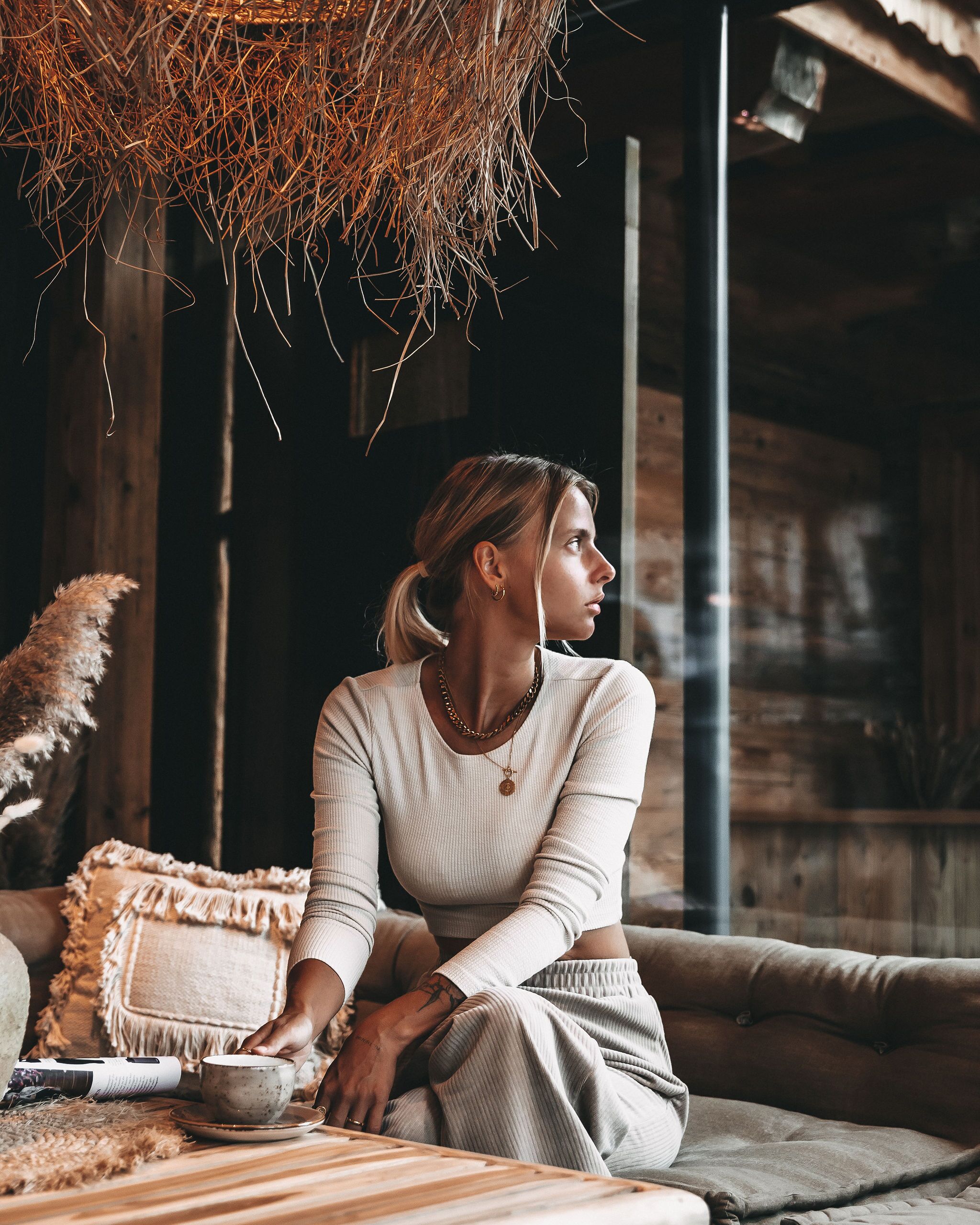 A person sitting on a couch in a rustic room with wooden walls and a hanging straw decoration.